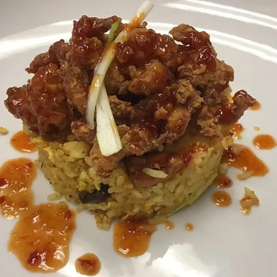 Crispy fried chicken pieces with sweet chili sauce and green onions, served over a bed of rice.