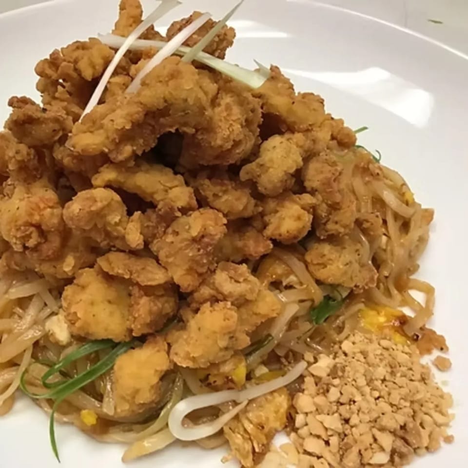Charm Thai Cuisine's Pad Thai with crispy fried chicken, garnished with green onions and peanuts.