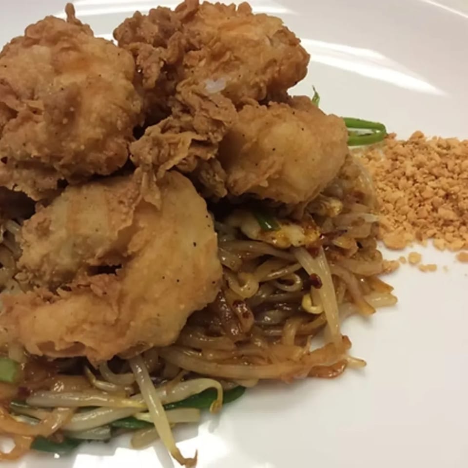 Charm Thai Cuisine's crispy fried chicken pieces atop a bed of stir-fried noodles with bean sprouts.