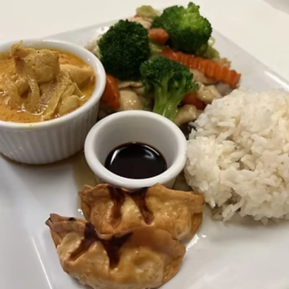 A Thai meal with red curry, stir-fried vegetables, rice, fried wontons, and soy sauce.