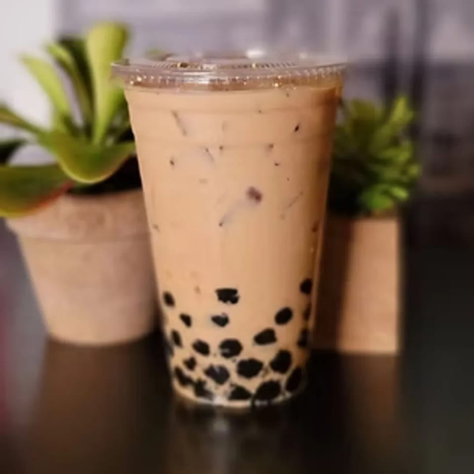 A plastic cup of Charm Thai Cuisine's iced Thai bubble tea with tapioca pearls and ice.