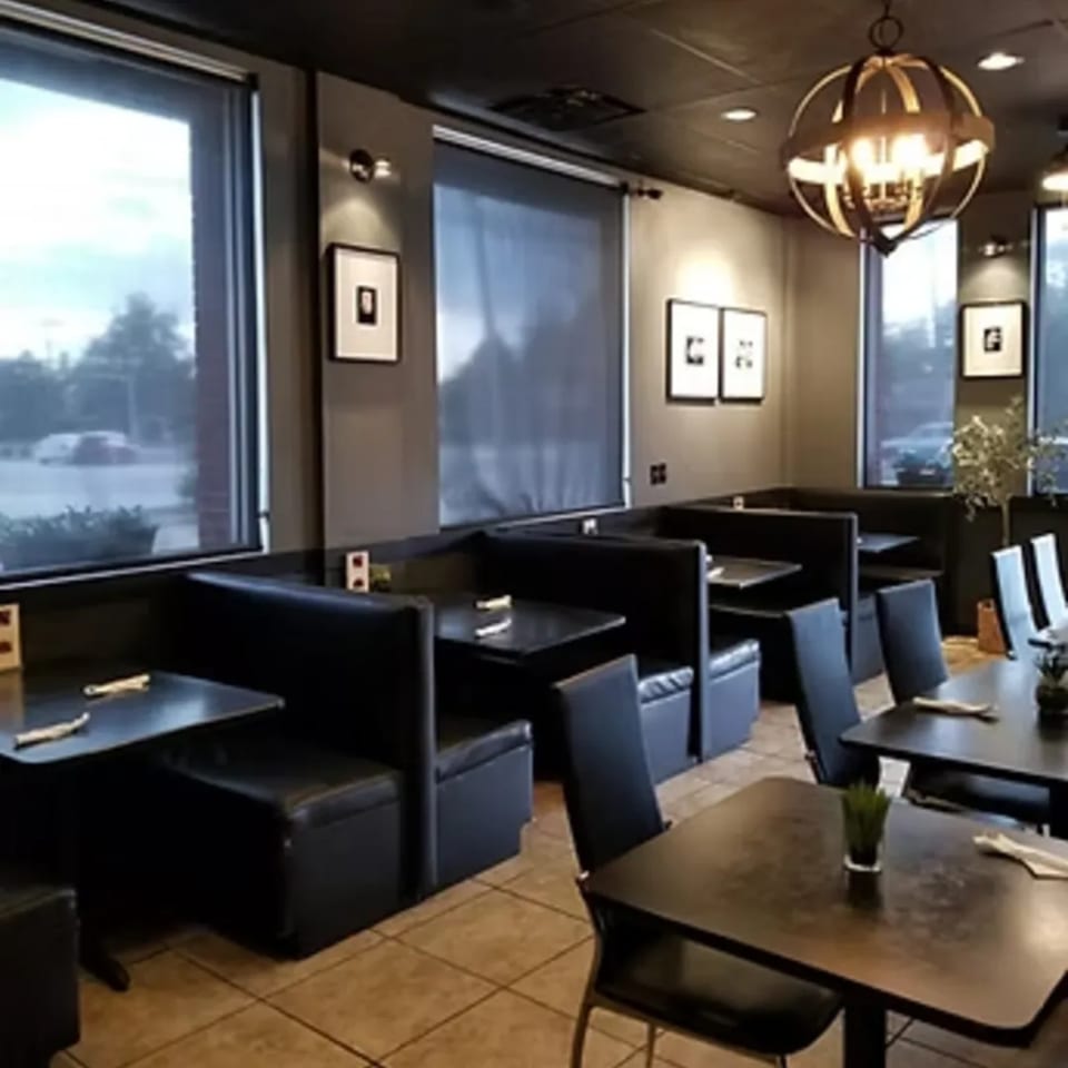 Interior of Charm Thai Cuisine with dark booths, tables, and a decorative chandelier.