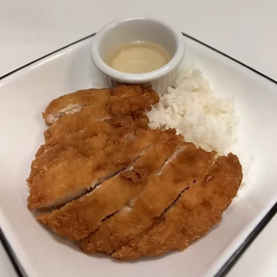 Crispy fried chicken cutlets, sliced and served with white rice and a small bowl of sauce.