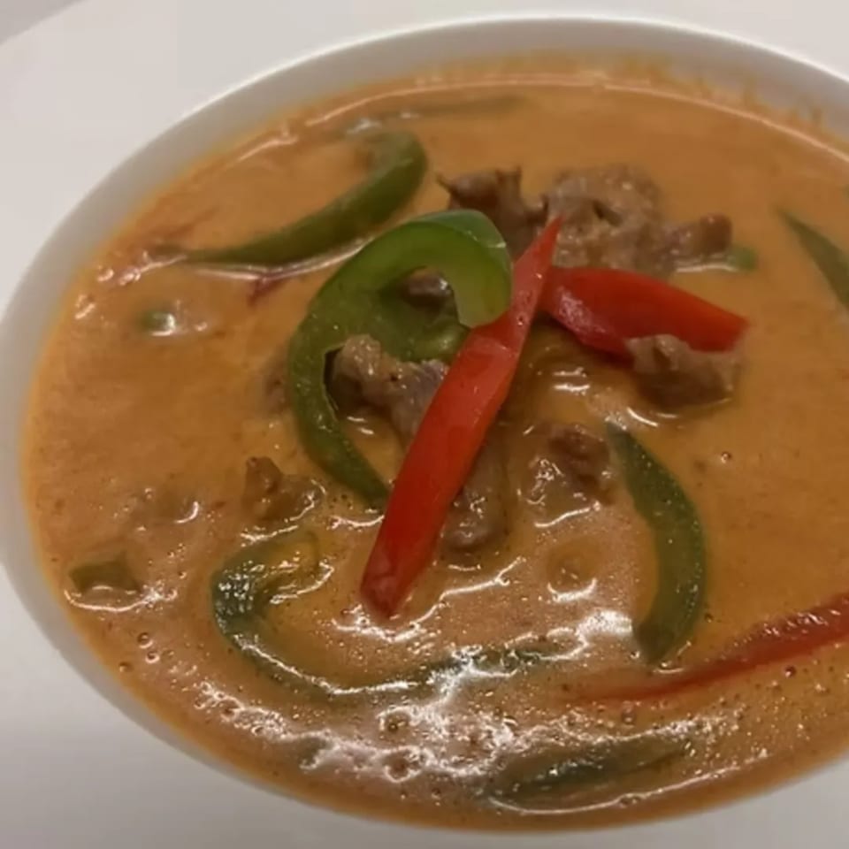 Close-up of Charm Thai Cuisine's red curry with beef, green and red bell peppers.