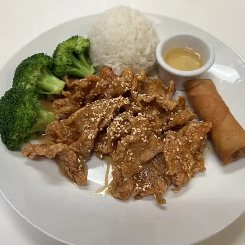 Charm Thai Cuisine's sesame chicken with broccoli, white rice, a spring roll, and dipping sauce.
