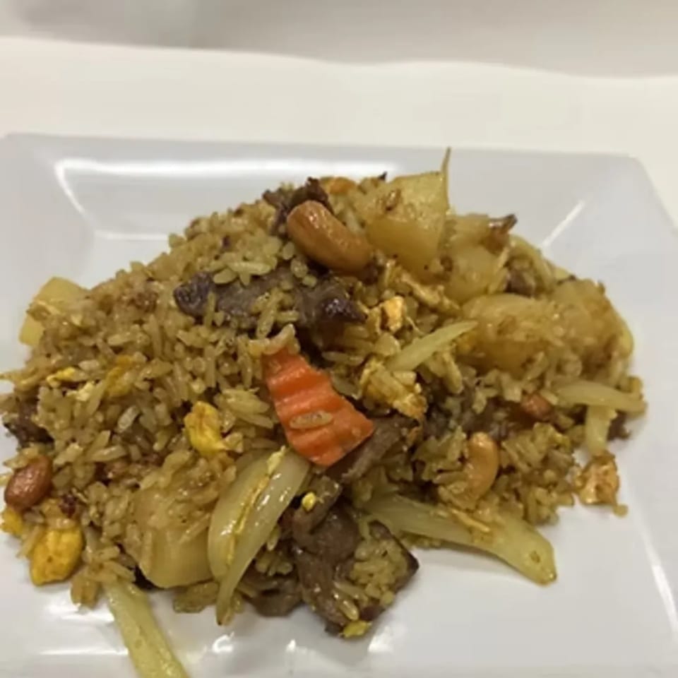 Charm Thai Cuisine's pineapple fried rice with beef, cashews, and vegetables on a white plate.