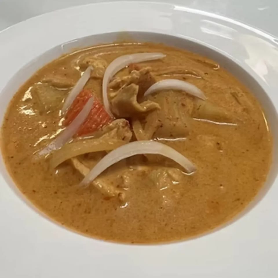Charm Thai Cuisine's red curry with chicken, onions, and red bell peppers in a white bowl.