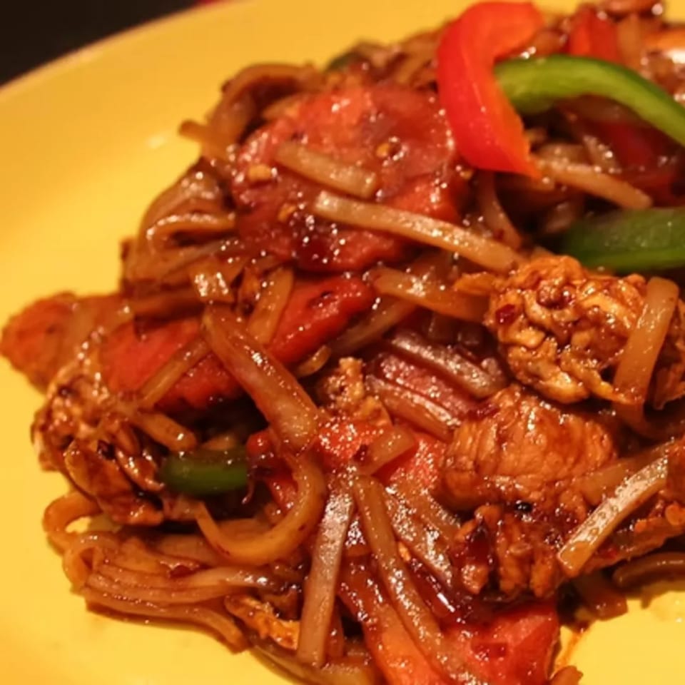 Close-up of Charm Thai Cuisine's stir-fried noodles with chicken, red and green bell peppers.