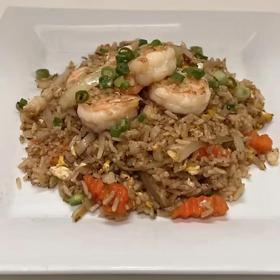 Charm Thai Cuisine's shrimp fried rice with carrots, onions, and green onions on a white plate.