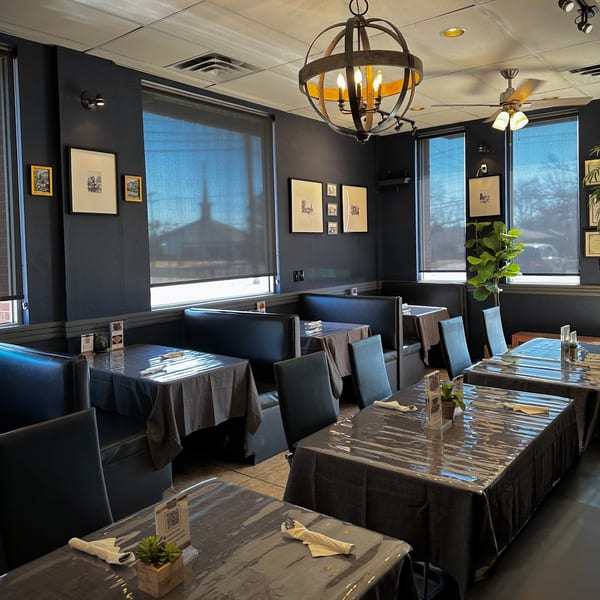 Interior of Charm Thai Cuisine with dark blue walls, black booths, and tables set with dark tablecloths.