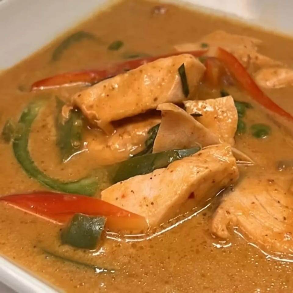 Charm Thai Cuisine's red curry with chicken, green and red bell peppers in a white bowl.