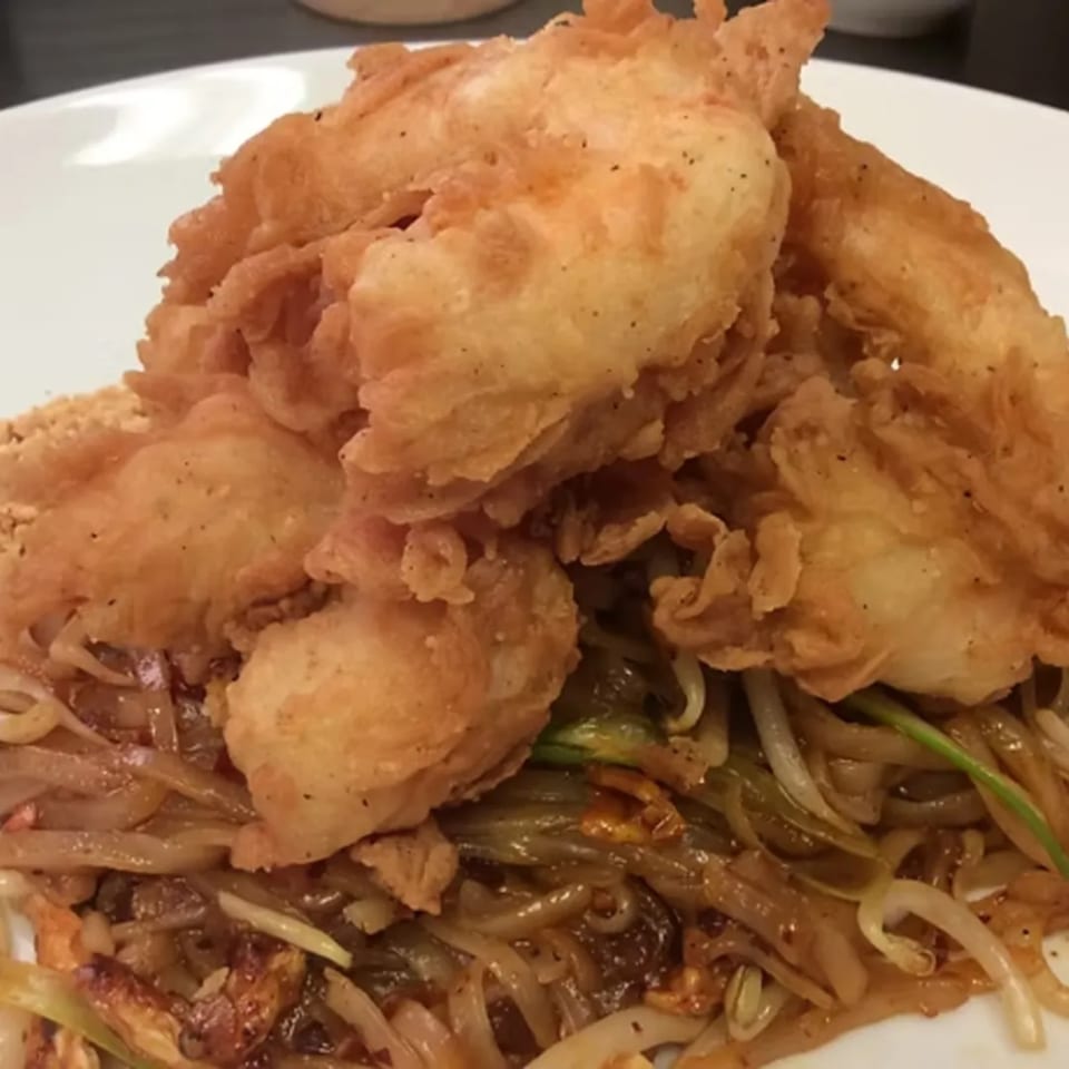 Close-up of crispy fried chicken pieces atop a bed of Charm Thai Cuisine's Pad Thai noodles.