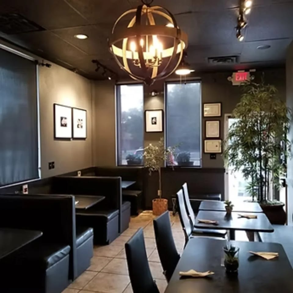 Interior of Charm Thai Cuisine with dark booths, tables, and a decorative chandelier.