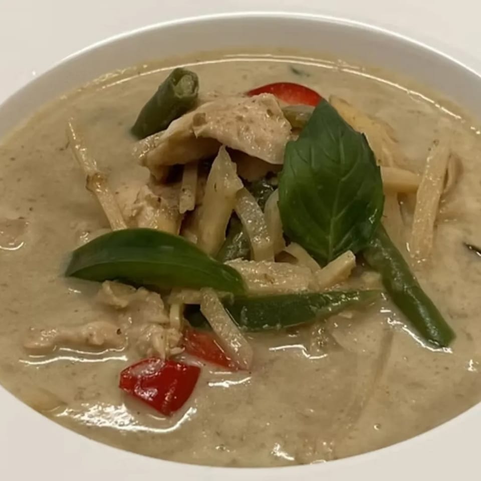 Close-up of Charm Thai Cuisine's green curry with chicken, bamboo shoots, red peppers, and basil.