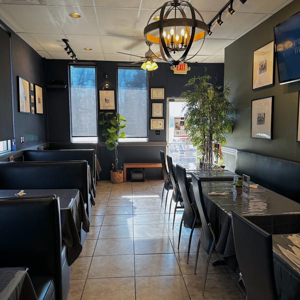 Interior of Charm Thai Cuisine with dark walls, booth seating, and tables set for dining.