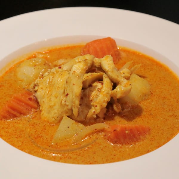 Charm Thai Cuisine's yellow curry with chicken, potatoes, and carrots in a white bowl.