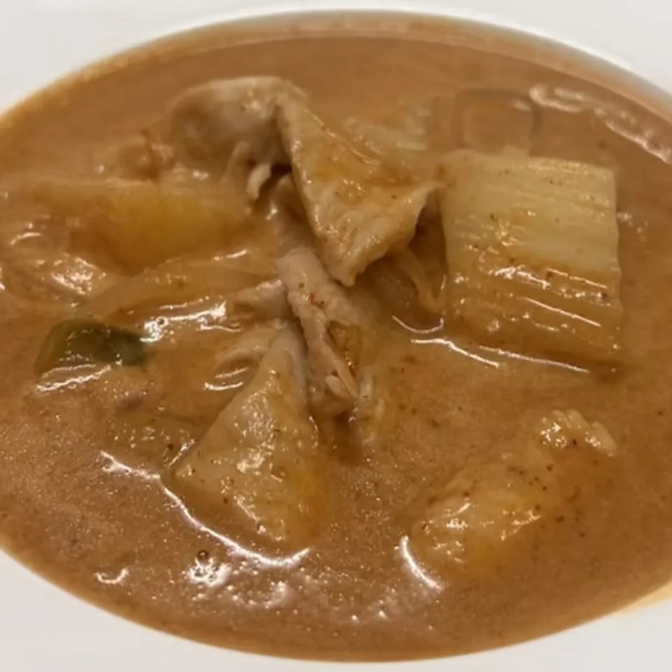 Close-up of Charm Thai Cuisine's Massaman Curry with chicken, potatoes, and onions in a rich brown sauce.