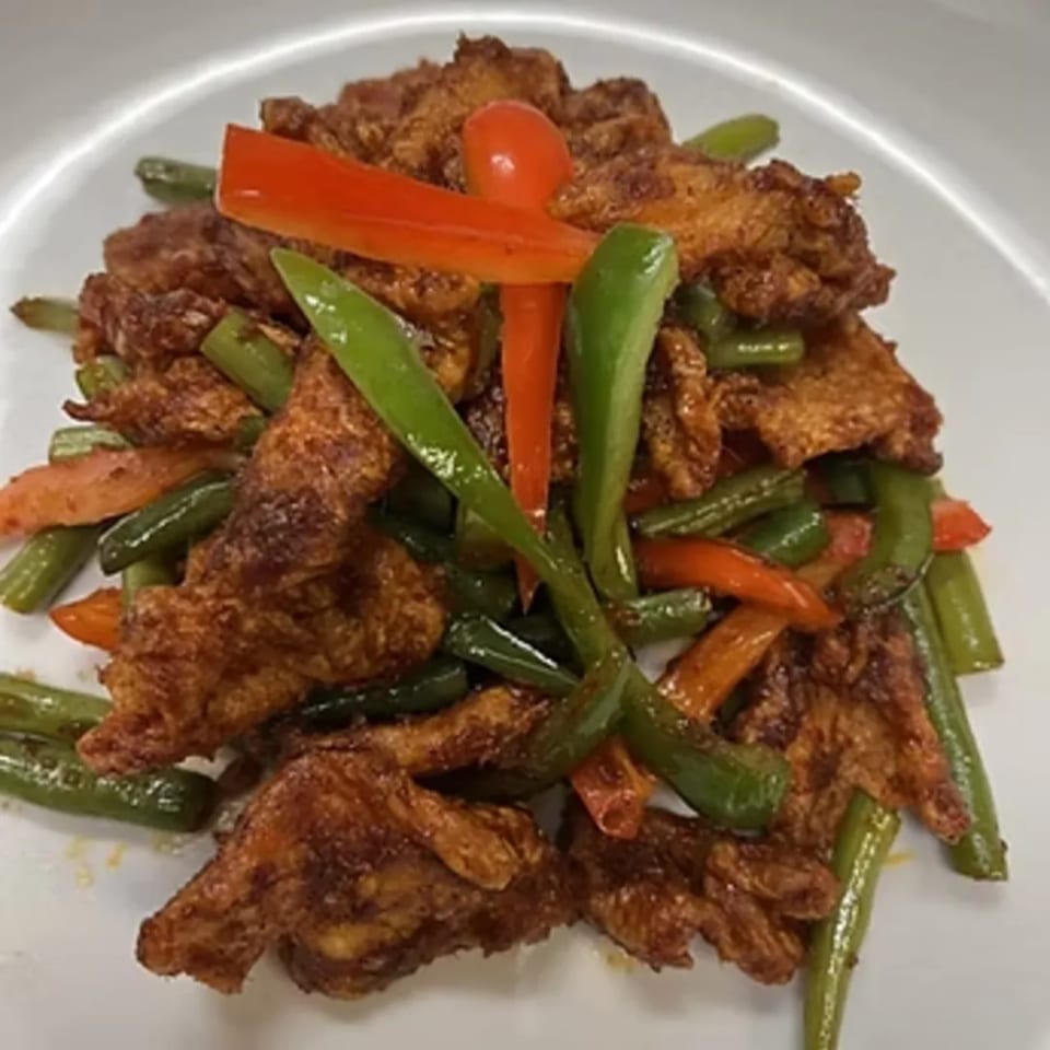 Charm Thai Cuisine's crispy fried chicken with green beans and red bell peppers on a white plate.