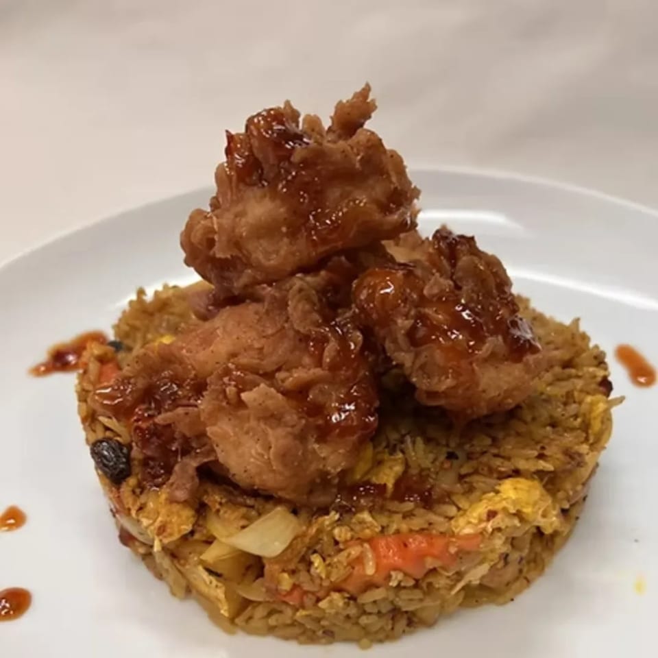 Charm Thai Cuisine's fried rice topped with crispy chicken pieces drizzled with a sweet sauce.