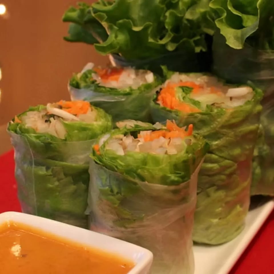 Fresh Charm Thai spring rolls filled with lettuce, carrots, and rice, served with peanut sauce.